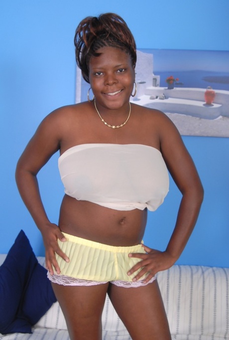 Older black woman Athena holds her large breasts while getting undressed