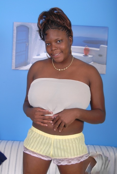 Older black woman Athena holds her large breasts while getting undressed