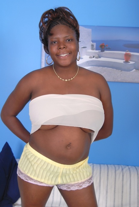 Older black woman Athena holds her large breasts while getting undressed