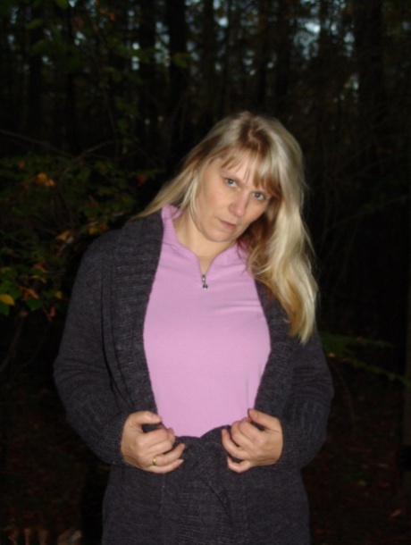 Mature blonde Sweet Susi shows her naked ass by a stack of firewood