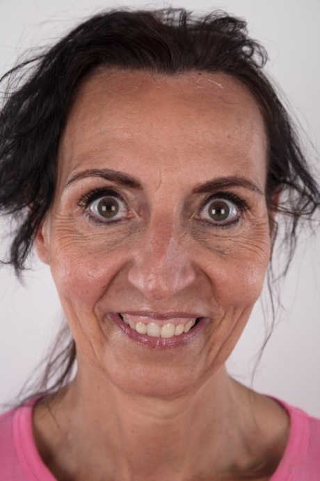 Mature woman Klaudie stands naked after removing her clothing in solo action