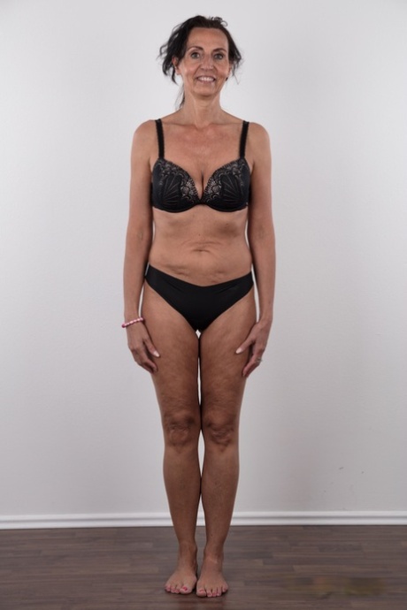 Mature woman Klaudie stands naked after removing her clothing in solo action
