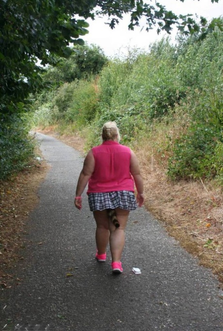 Fat UKwoman Lexie Cummings walks a path sporting a raccoon tail butt plug