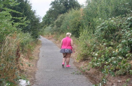 Fat UKwoman Lexie Cummings walks a path sporting a raccoon tail butt plug