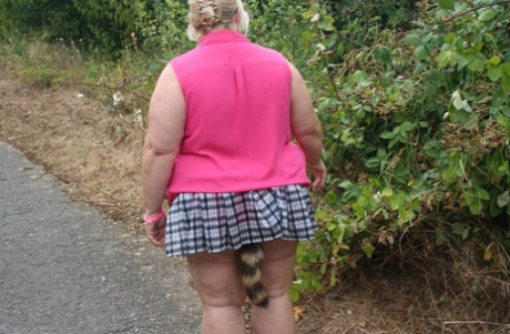 Fat UKwoman Lexie Cummings walks a path sporting a raccoon tail butt plug