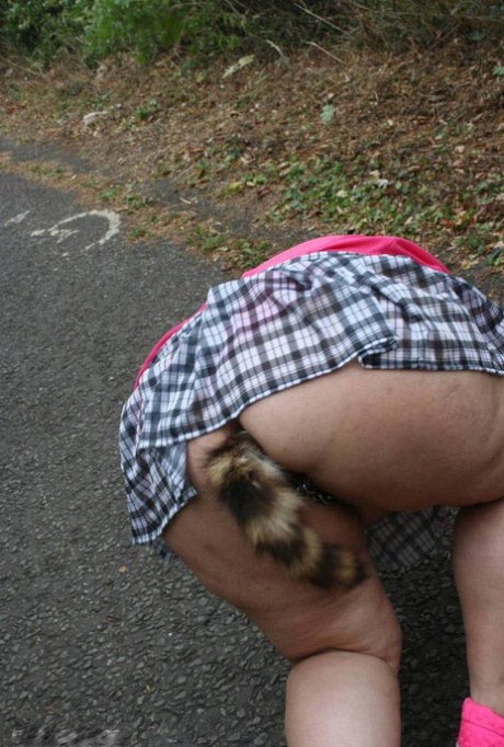 Fat UKwoman Lexie Cummings walks a path sporting a raccoon tail butt plug