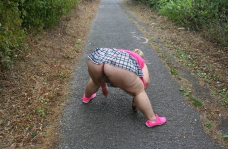 Fat UKwoman Lexie Cummings walks a path sporting a raccoon tail butt plug