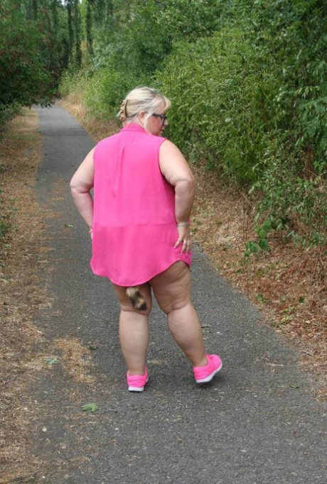 Fat UKwoman Lexie Cummings walks a path sporting a raccoon tail butt plug