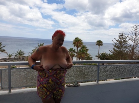 Obese nan with spiky red hair unveils her tits on balcony before posing naked