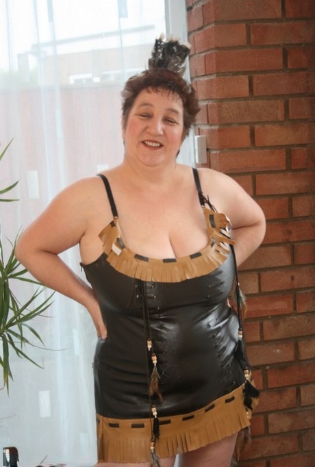 Sick mature woman Kinky Carol models leather lingerie in black boots