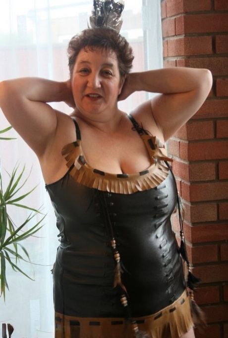 Sick mature woman Kinky Carol models leather lingerie in black boots