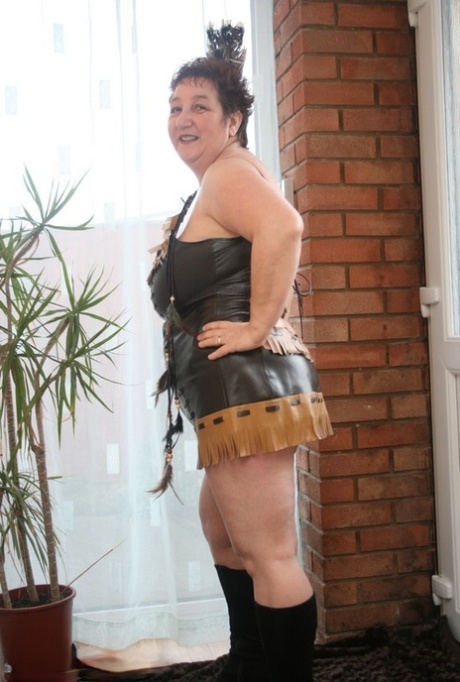 Sick mature woman Kinky Carol models leather lingerie in black boots