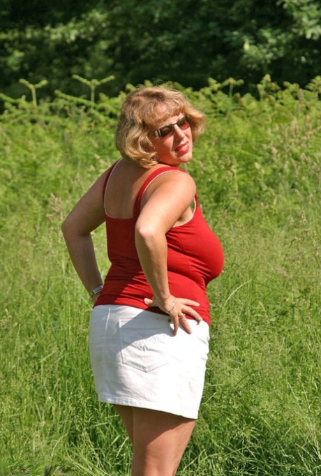 Fat mature lady Curvy Claire uncovers her large tits and big ass in a field