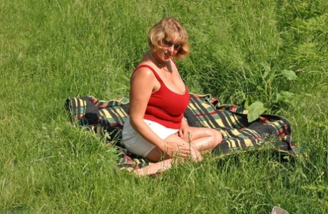 Fat mature lady Curvy Claire uncovers her large tits and big ass in a field