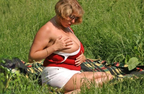 Fat mature lady Curvy Claire uncovers her large tits and big ass in a field