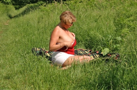 Fat mature lady Curvy Claire uncovers her large tits and big ass in a field