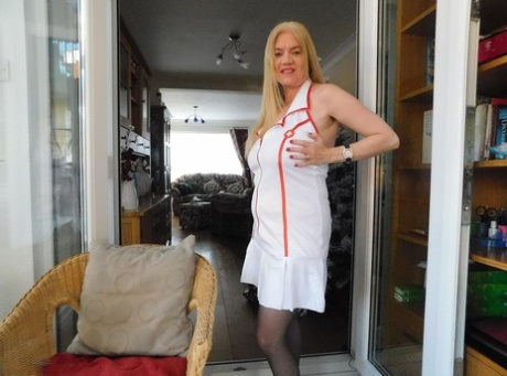 Older British nurse Lily May unzips her uniform on a wicker chair