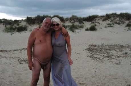 Mature blonde Dimonty eats a frozen treat after posing nude on a beach