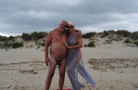 Mature blonde Dimonty eats a frozen treat after posing nude on a beach
