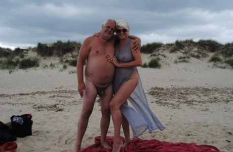Mature blonde Dimonty eats a frozen treat after posing nude on a beach