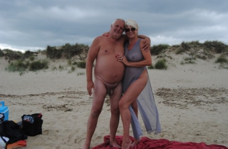 Mature blonde Dimonty eats a frozen treat after posing nude on a beach