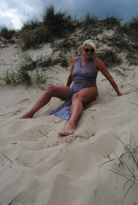 Mature platinum blonde Dimonty models at the beach in see through clothing