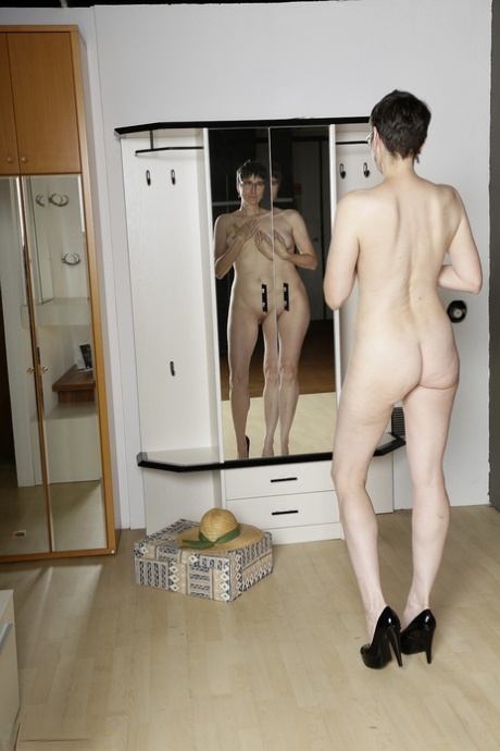 Mature amateur admires her naked body in a mirror while wearing black heels