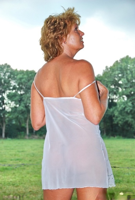 Older amateur with short red hair gets naked by a barbed wire fence