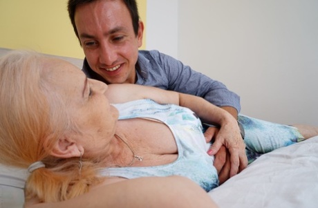 Blonde granny kisses her toy boy after they fuck on top of a bed