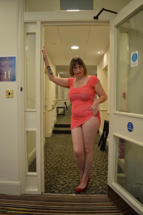 Leggy aged woman Barby Slut frees her big tits and bald cunt from a pink dress