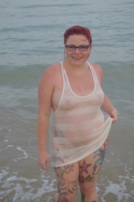 Tattooed redhead poses nude on a beach before masturbating on a toilet seat