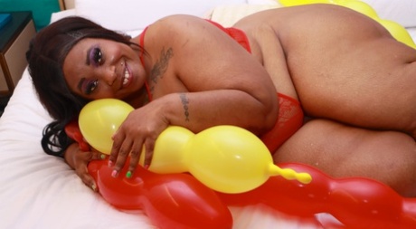 Ebony SSBBW Simone Thyke gets up close and personal with balloons on a bed