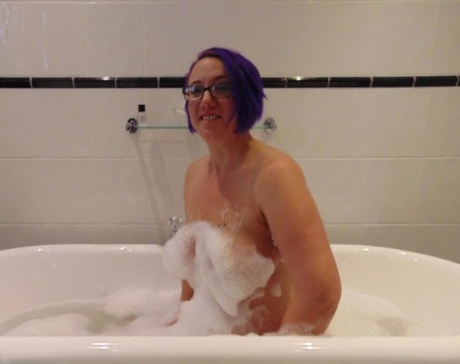 Mature plumper Sara Banks sports dyed hair while taking a bubble bath