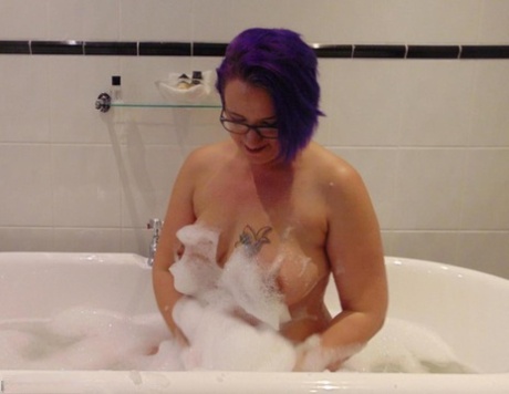 Mature plumper Sara Banks sports dyed hair while taking a bubble bath