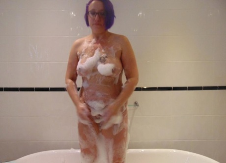 Mature plumper Sara Banks sports dyed hair while taking a bubble bath