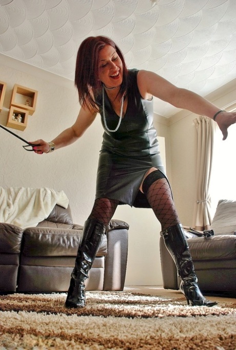 British redhead Juicey Janey hikes up a leather dress while wielding a flogger