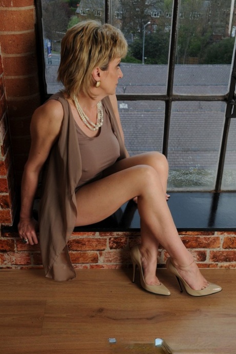 Older UK blonde Lady Sonia shows her bare legs while wearing a dress and heels