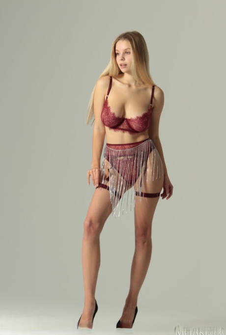 Beautiful blonde teen Mila Amour unveils her augmented tits while going nude