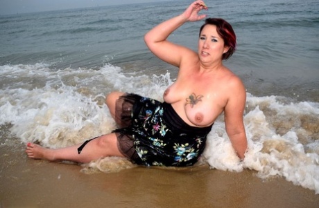 Older lady Sara Banks shows her tits and pussy on a beach in the surf