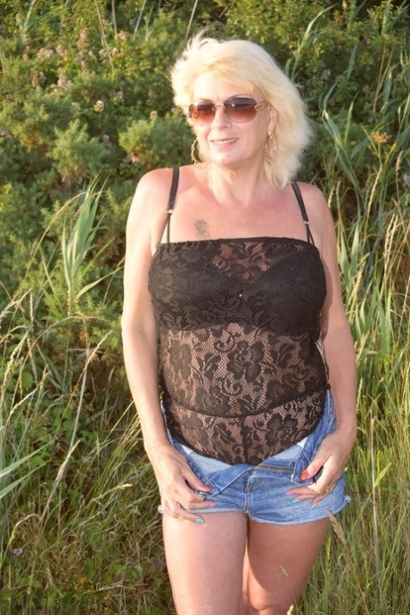 Older blonde Dimonty displays her big boobs at an outdoor location
