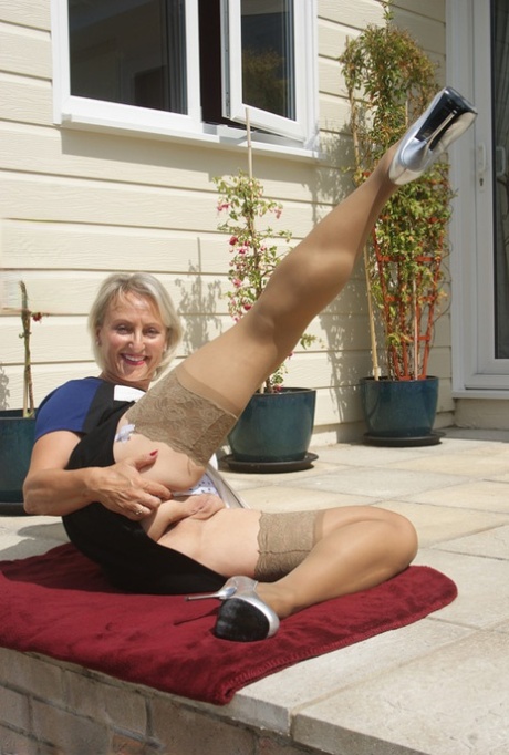 Leggy mature dame in stockings exposing big tits outdoors in high heels