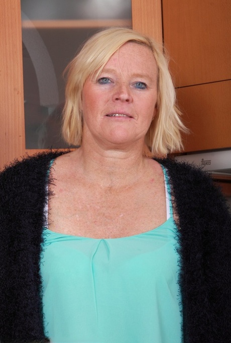 Mature housewife with blonde hair and blue eyes strips naked in her kitchen