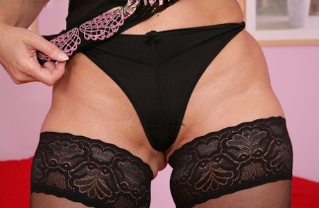 Lusty mature blonde in stockings undressing and fingering her gash