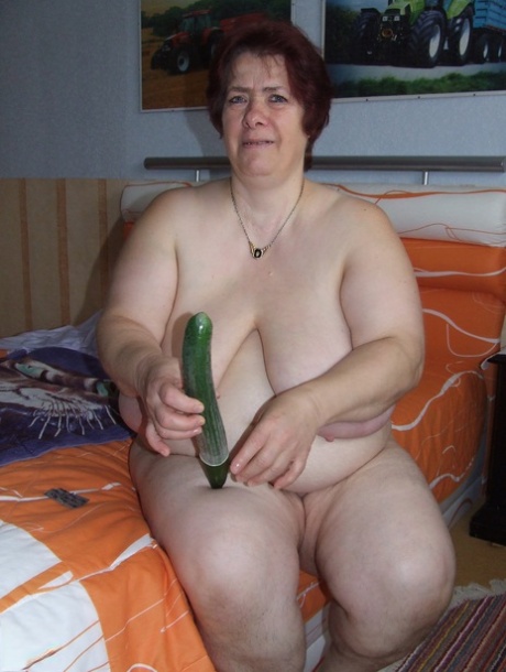Fat mature Corinna puts a condom on a huge cucumber and masturbates