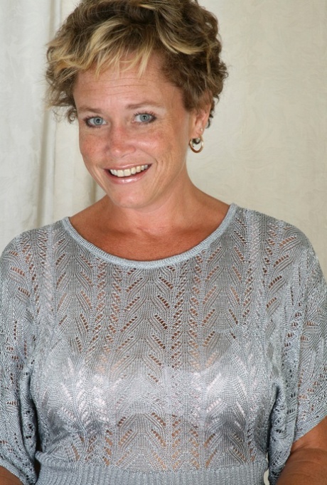 Blue eyed MILF with big tits Ariel undresses and poses on a table