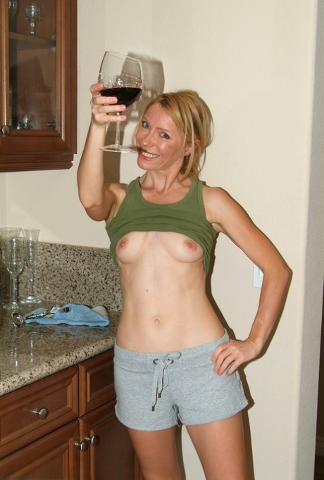 Lovely MILF Olga strips naked and poses while drinking wine in the kitchen
