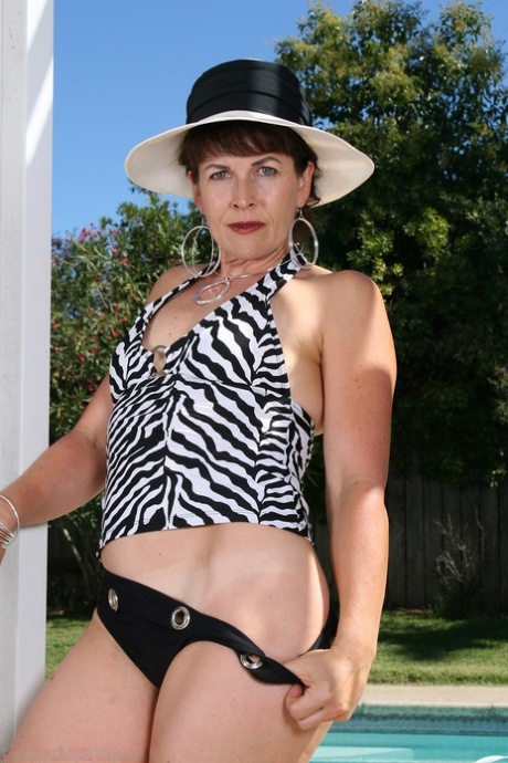 Kinky mature amateur Andie doffs her clothes and poses nude poolside