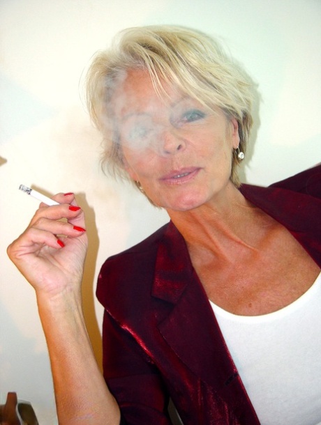 Mature lady Justine exposes her saggy tanned tits while smoking a cigarette
