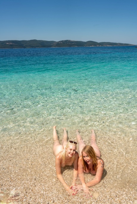 Moms with big booties Mackenzie Page and Miss Melissa pose nude on the beach