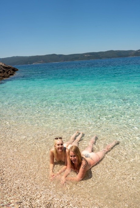 Moms with big booties Mackenzie Page and Miss Melissa pose nude on the beach